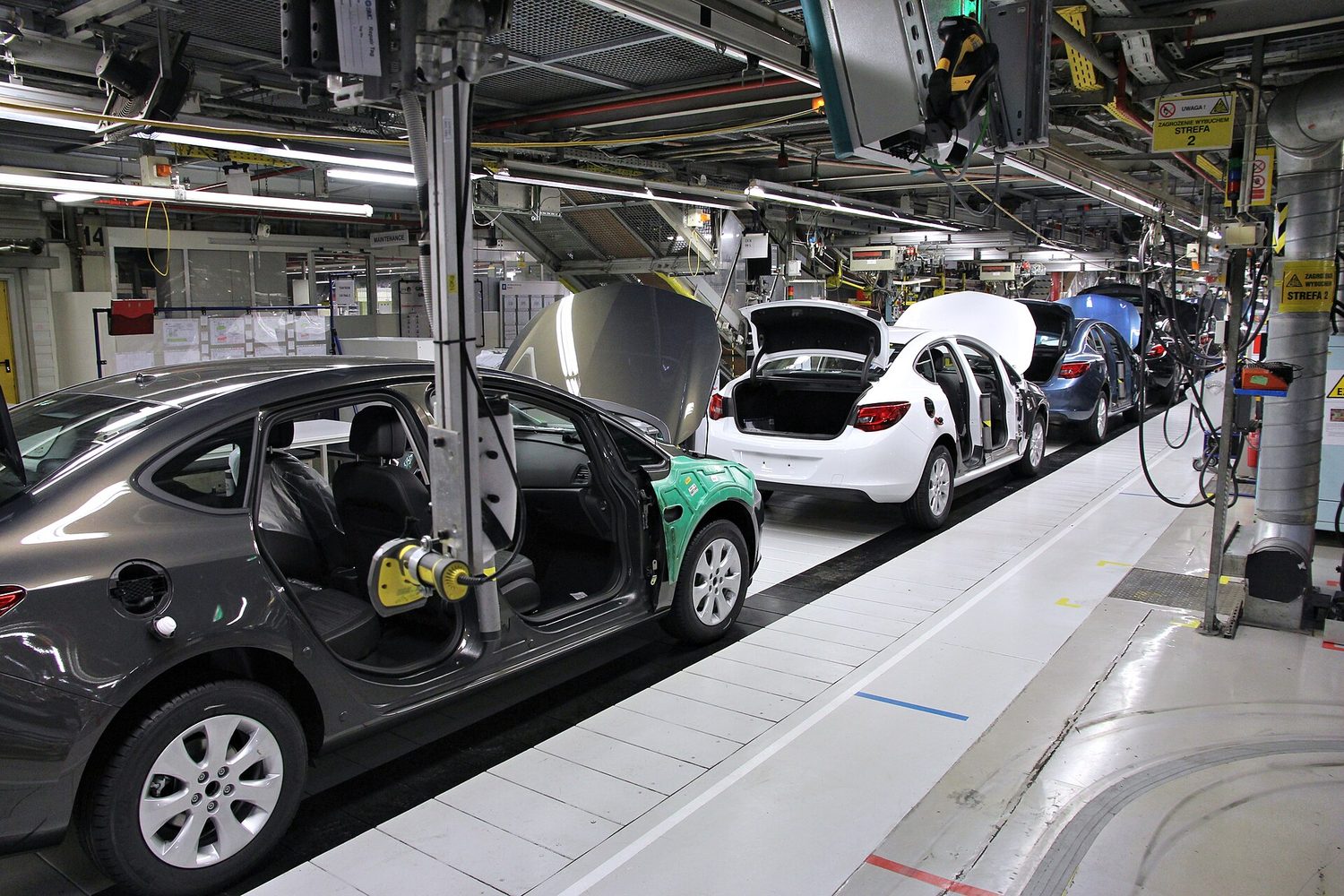A car assembly line: capital (machines and robots) plus the division of labour, each worker repeating one task