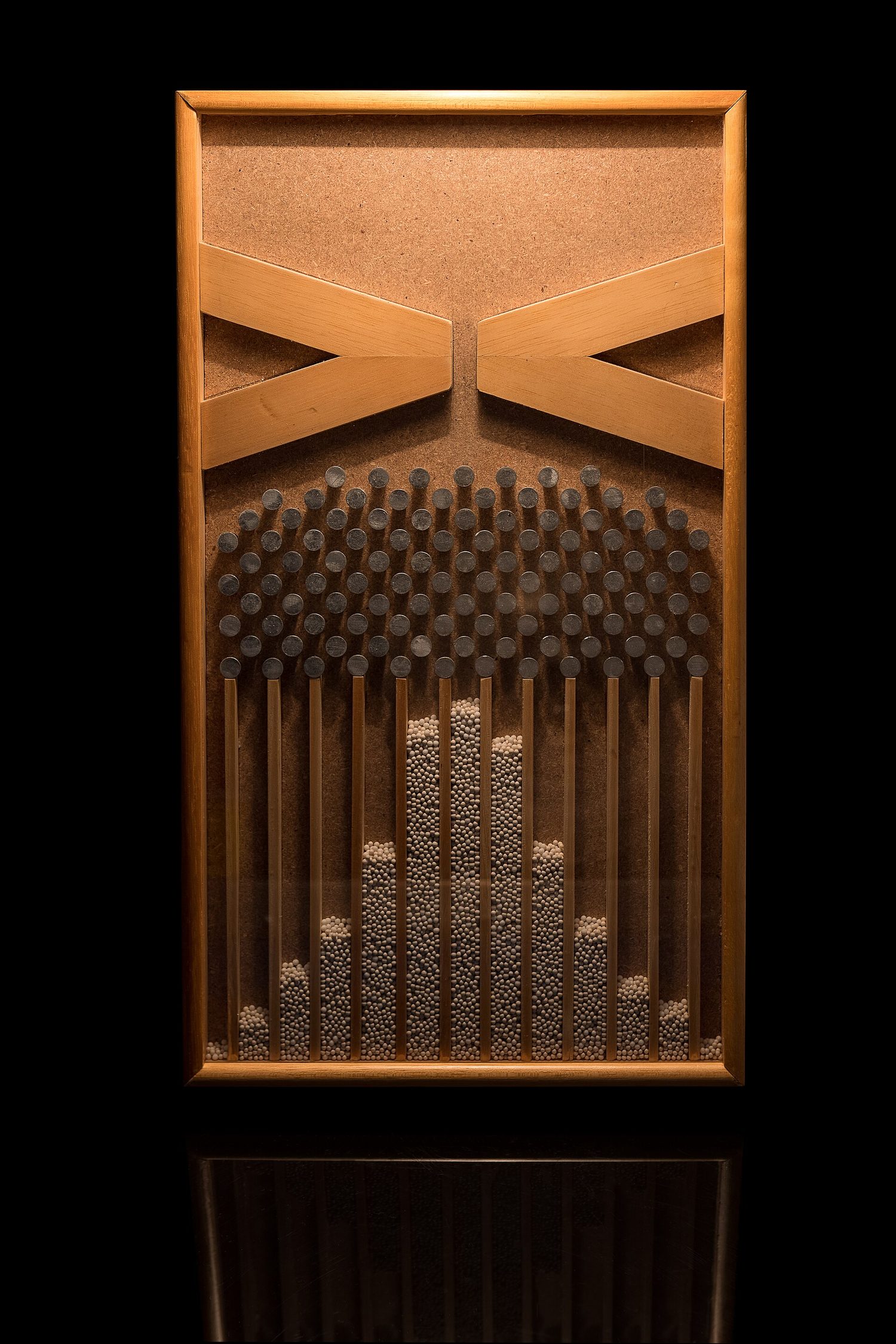 A Galton board: balls fall through rows of pegs and pile up into the bell-shaped normal distribution