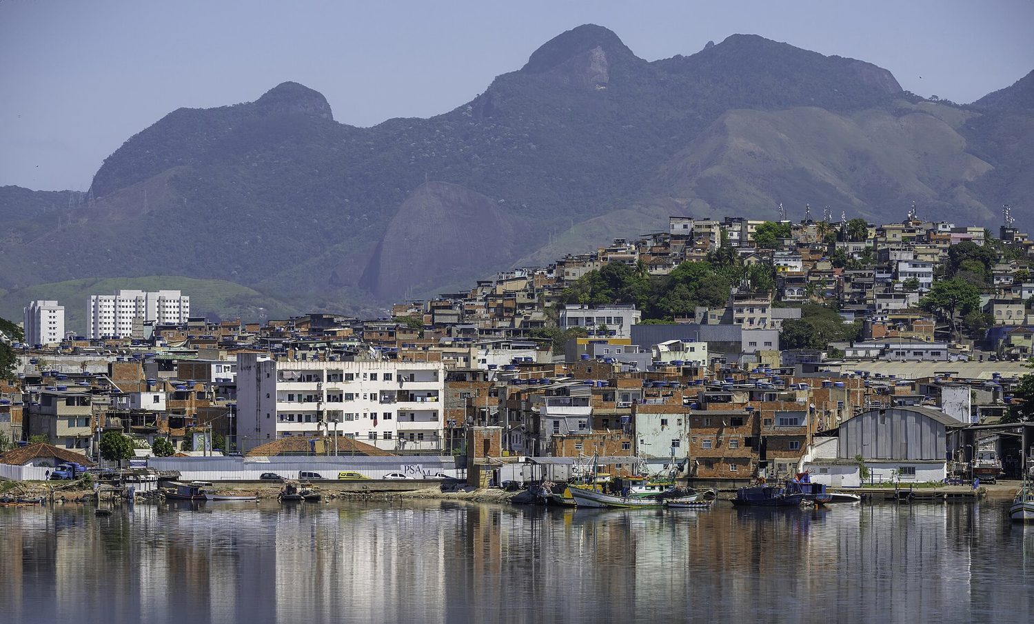 Densely packed self-built houses covering a steep hillside above the water in Rio de Janeiro