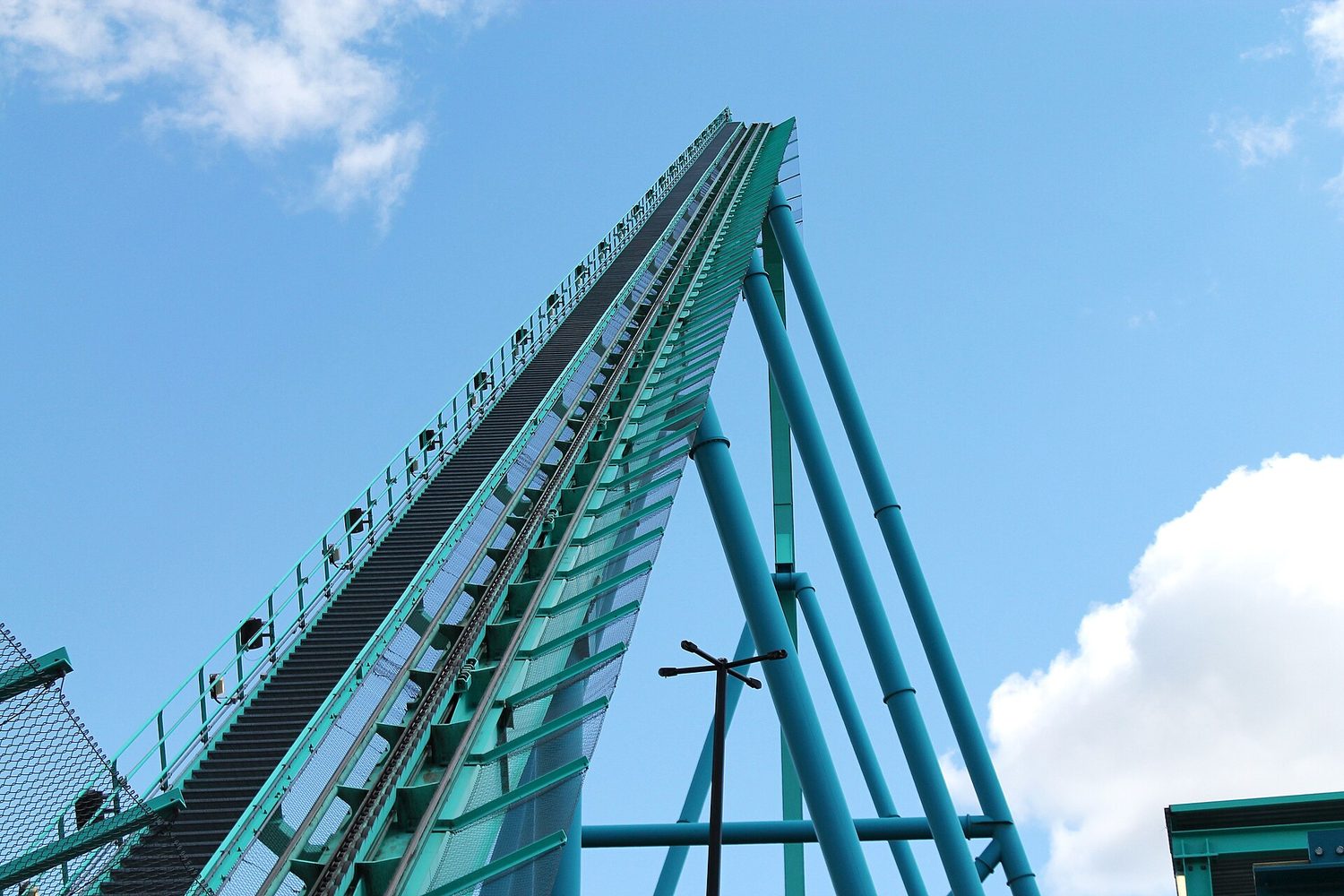 A roller coaster with tall loops of green and red track against the sky
