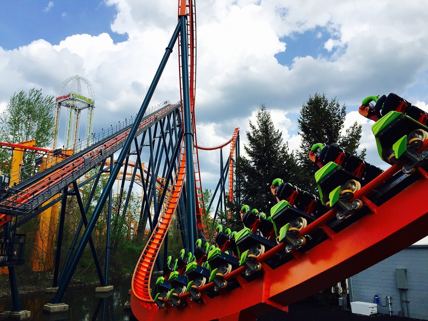 Roller-coaster cars running down a curved track, with a tall hill behind