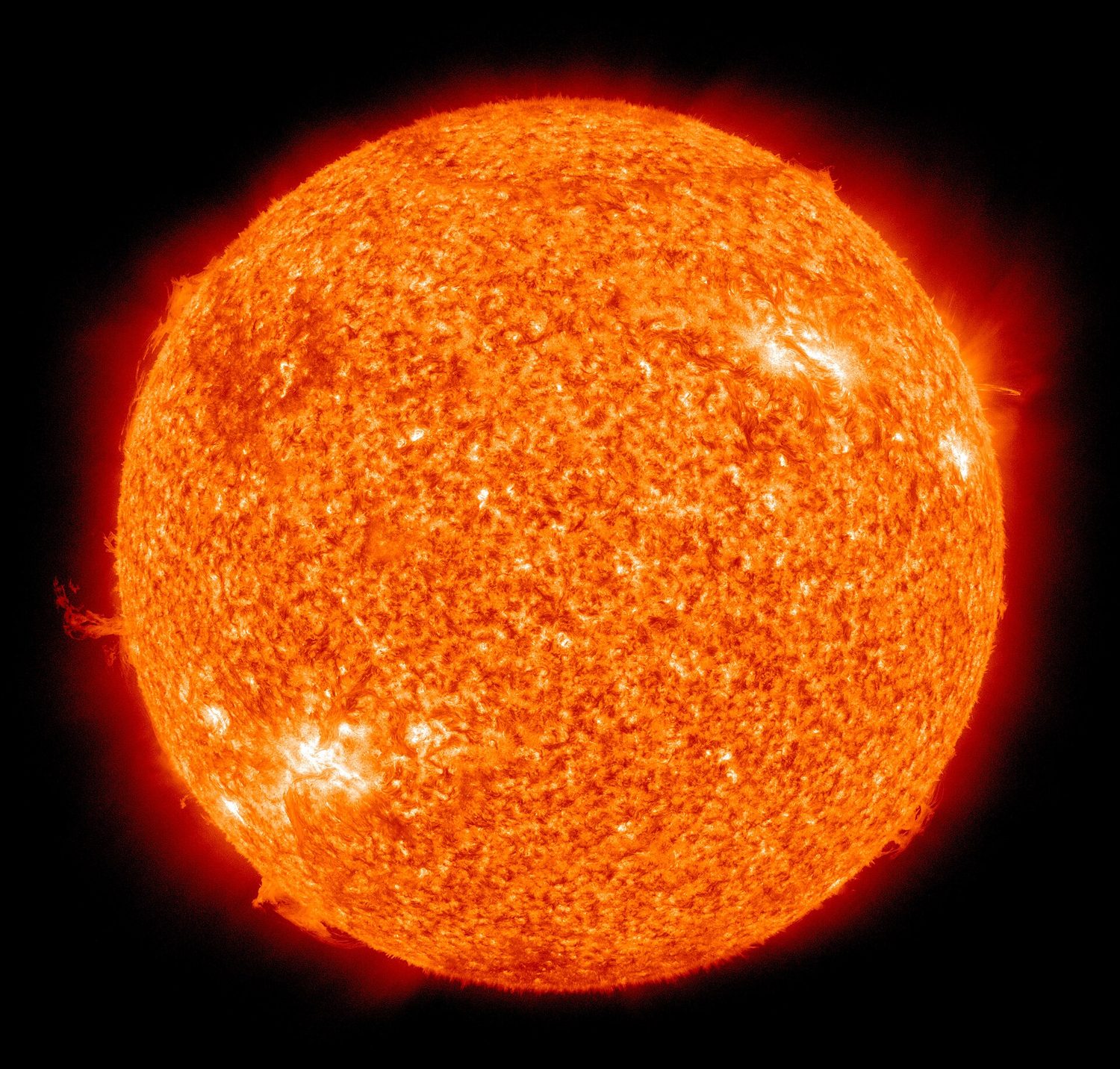 The Sun shown as a glowing orange disc with a bright prominence at the edge, imaged in ultraviolet light by NASA's Solar Dynamics Observatory